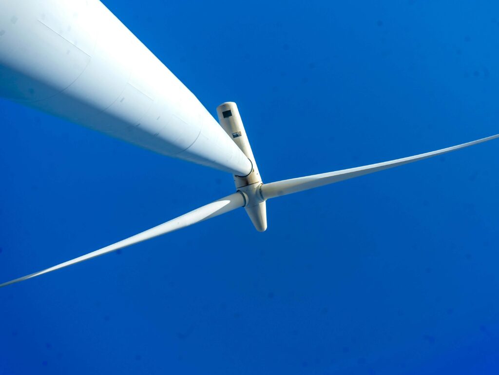 Close-up of a wind turbine against a blue sky (Photo by Mario Amé on Unsplash)